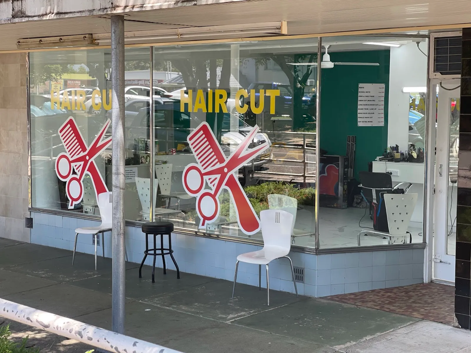 Salon window with scissors and comb decals and chairs inside